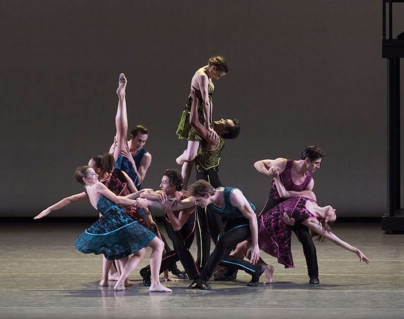 A mass of colorfully colored dancers strike virtuosic poses.